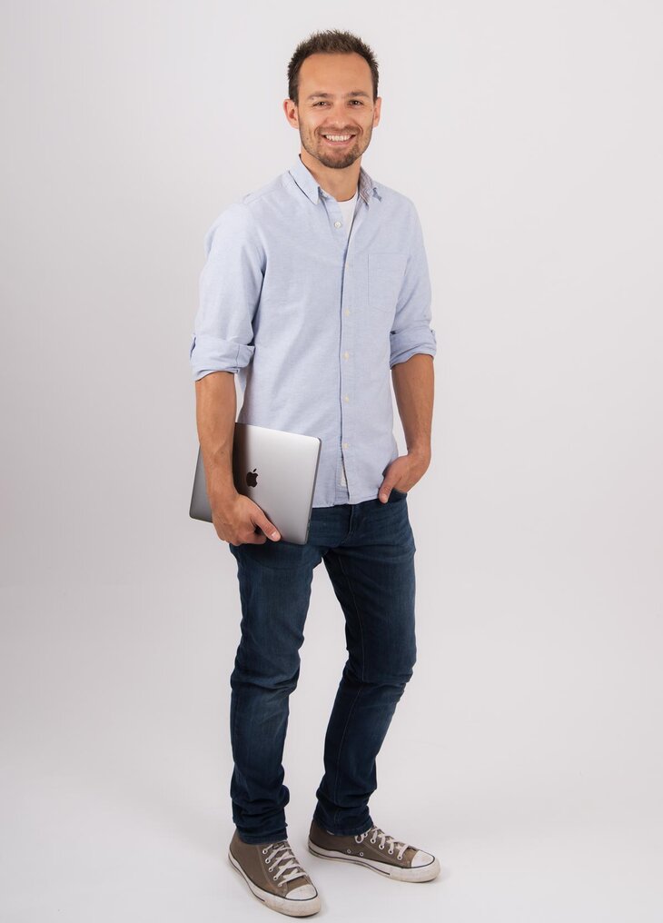 Christoph Bolda in hellblauem Hemd mit einem Laptop unter dem Arm
