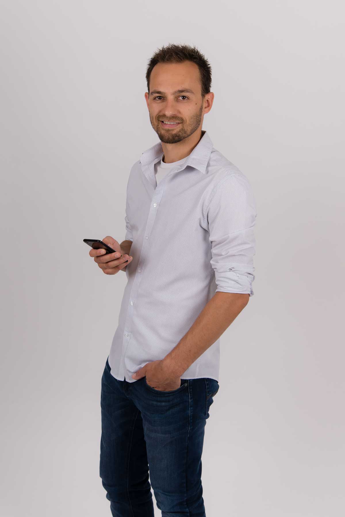 Christoph Bolda mit einem Smartphone in der Hand, Blick Richtung Kamera