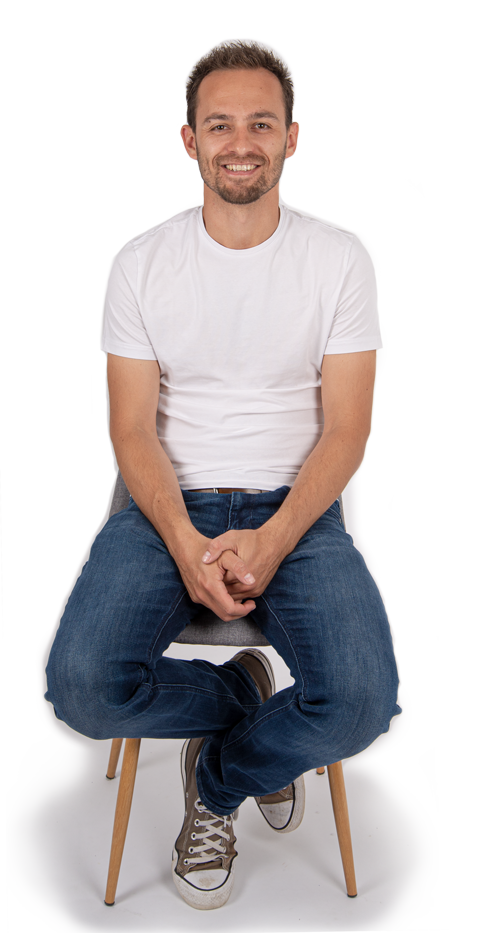 Christoph Bolda in weißem T-Shirt auf einem Stuhl